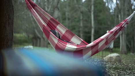 Eine-Person,-Die-Sich-In-Einer-Roten-Hängematte-Auf-Einem-Campingplatz-Im-Freien-Ausruht