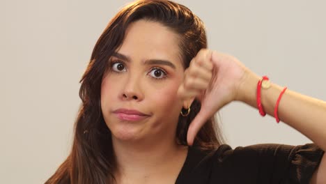 close up de una mujer haciendo un signo negativo con los pulgares hacia abajo