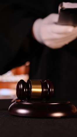 Judge preparing to make an important ruling with gavel and legal books in courtroom setting. Vertical video