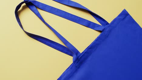 Video-of-yellow-canvas-bag-with-copy-space-on-blue-background