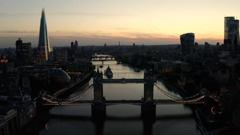 aerial view of london, river thames, and tower bridge just after the sun has set and the sky is lit