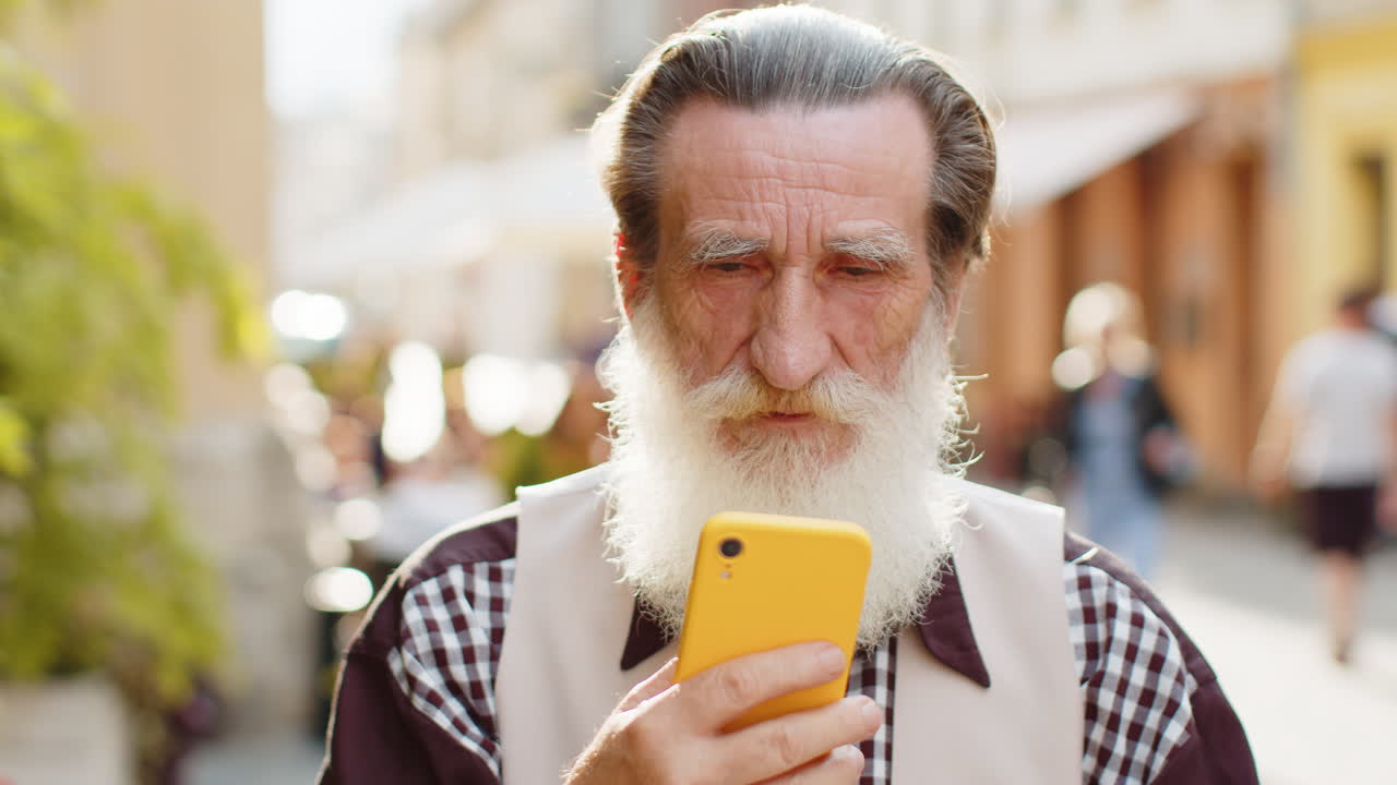 hombre de edad avanzada usar smartphone escribir mensajes de texto navegar por internet terminar el trabajo mirando a la cámara