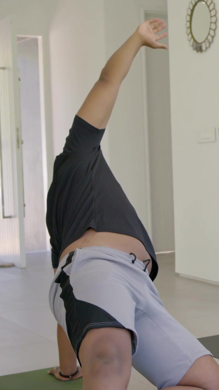Vídeo vertical: Mulher com fone de ouvido, ao sinal, fazendo alongamento sentada na sala de estar, tapetes, espaço para texto