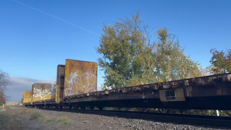 an empty freight train goes over railroad tracks on a blue-sky day