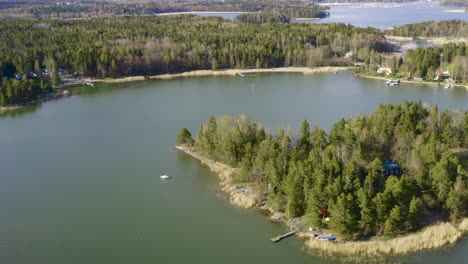 flying in a rotating pattern high above a forested island a beautiful lake and shoreline full of trees can be seen in all directions of the inviting recreational marina area.