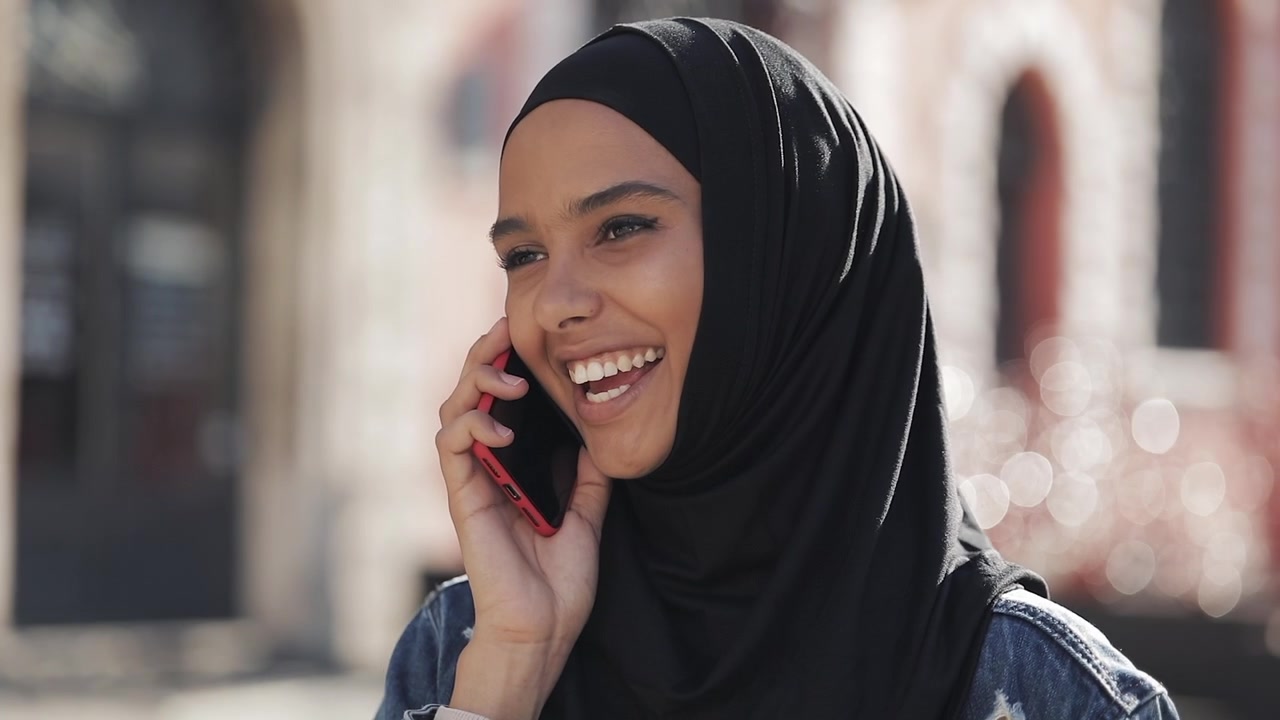 Giovane donna con hijab che parla allo smartphone all'aperto