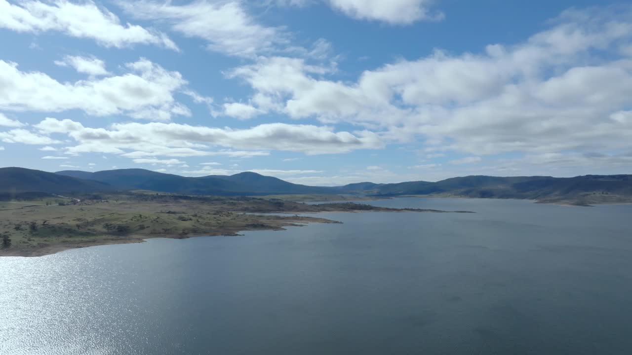 Aerial: Wide shot flying over Lake Jindabyne towards the mountains of kosciuszko national park, Australia
