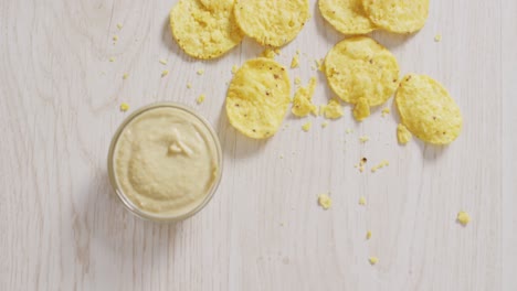 video of crisps and cheese dip on a wooden surface