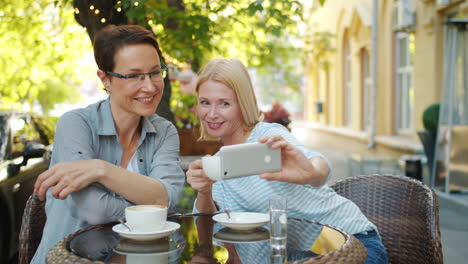 two women taking a selfie in a cafe