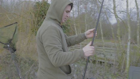 the angler puts the rod to the carp tent located on the island in the pond