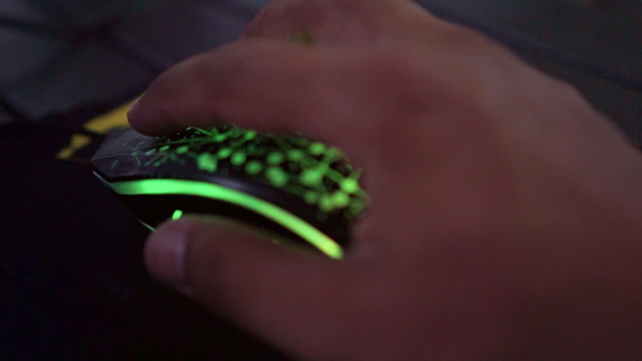 Hand operating illuminated mouse, close-up, technology interaction, computer navigation, modern workspace