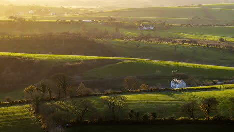 Time-lapse-of-rural-farming-landscape-with-farmhouse-in-grass-fields-and-hills-during-evening-sunlight-viewed-from-Keash-caves-in-county-Sligo-in-Ireland