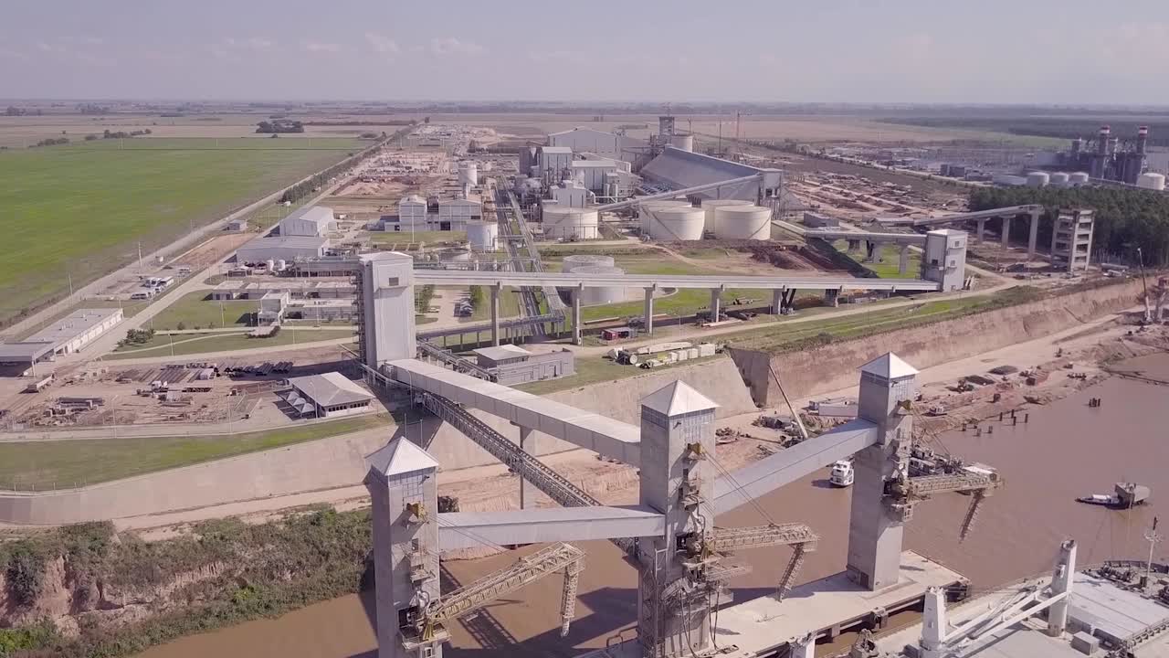 Aerial View of the Factory at the edge of the river carrying grains in a freighter