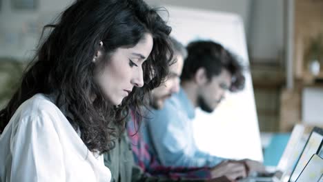 Side-view-of-focused-female-developer-working-with-laptop