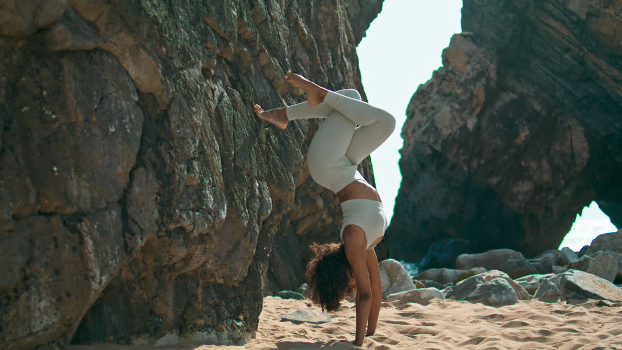 Young woman headstand exercising beach vertical. Girl practicing yoga on nature.