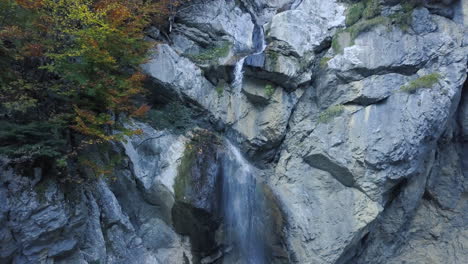 drone-flying-backwards,-facing-towards-a-waterfall-in-the-austrian-alps