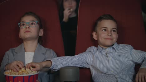 children eat popcorn in cinema. preschool children watching movie in cinema