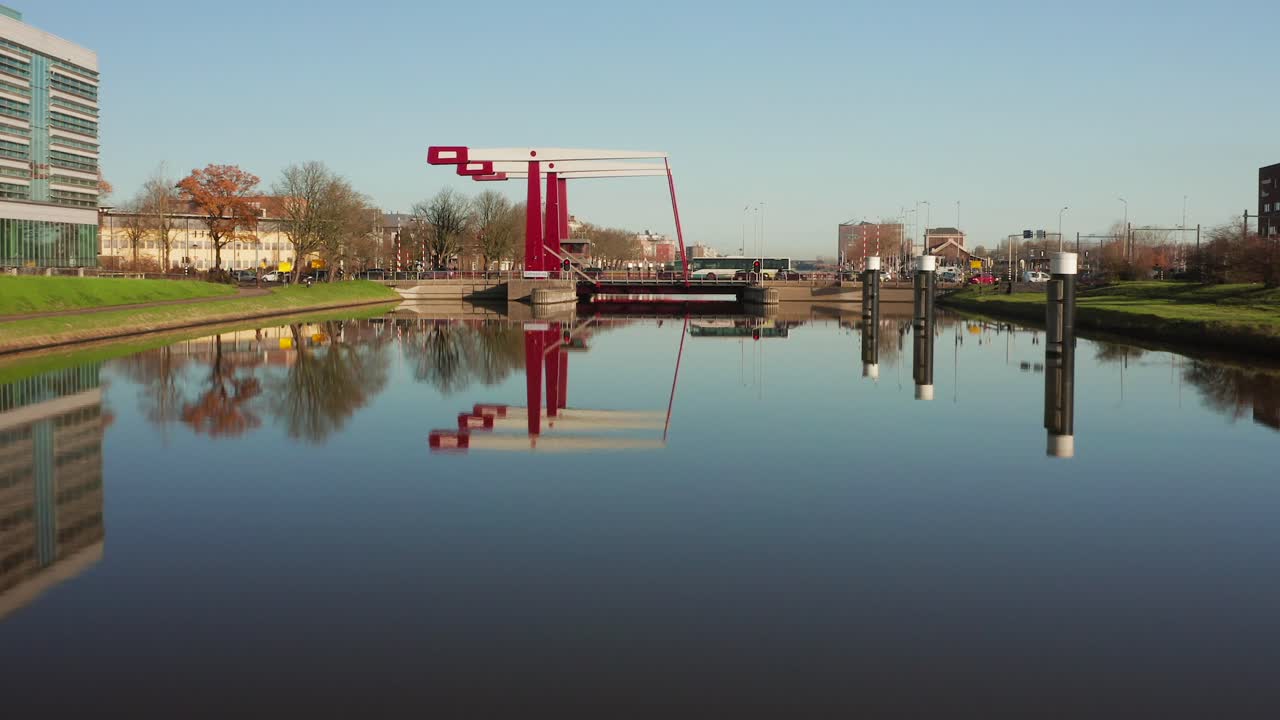 Low angle aerial shot flying towards a busy bridge in Middelburg with reflection on the water of the canal