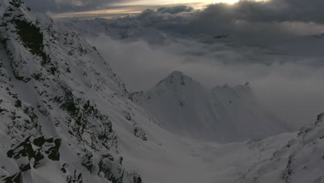 Toma-Panorámica-De-Drones-Cinematográficos-De-Montañas-Nevadas-Sobre-El-Paisaje-Nuboso-Durante-La-Puesta-De-Sol-A-Mediados-De-Invierno-Alpes-Austriacos-Kauntertal,-Austria