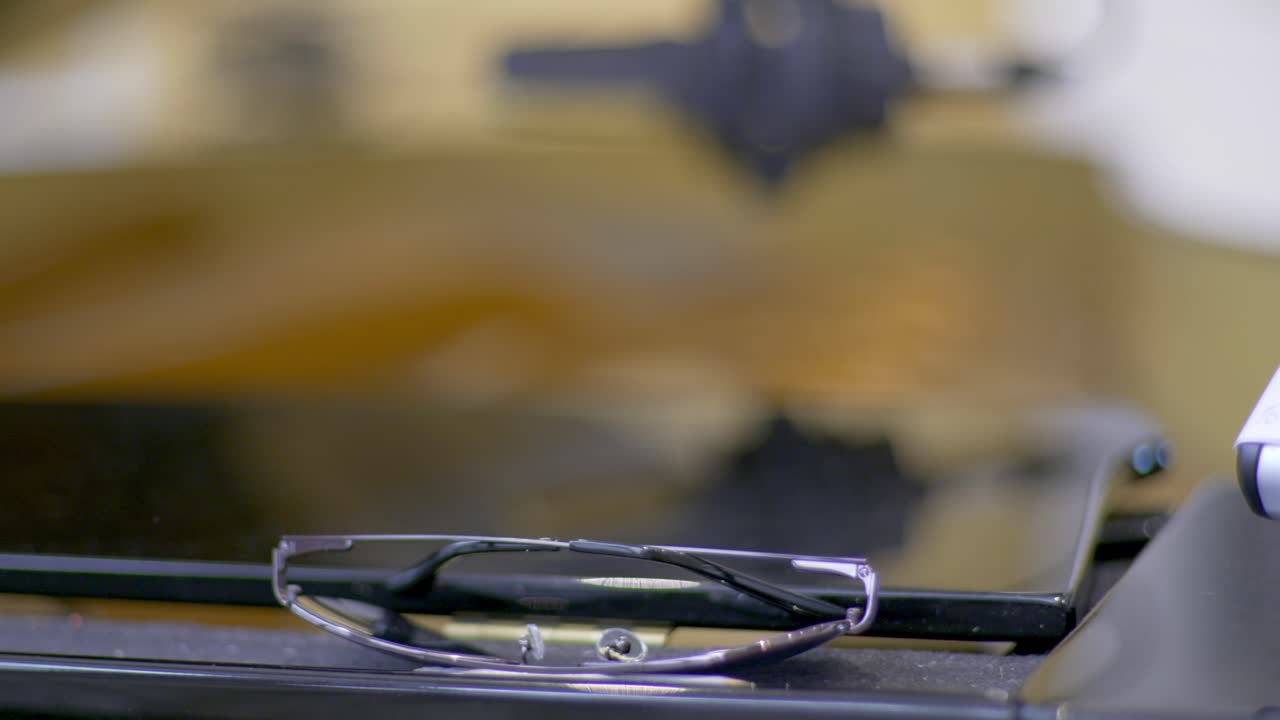 Close up of a musicians pair of sun glasses lying on s black piano with a microphone behind in the blurred background