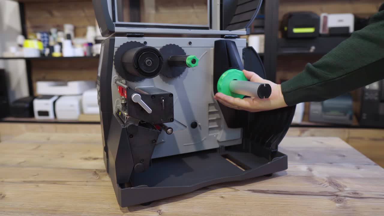 un hombre cambia la cinta en una impresora de etiquetas industriales