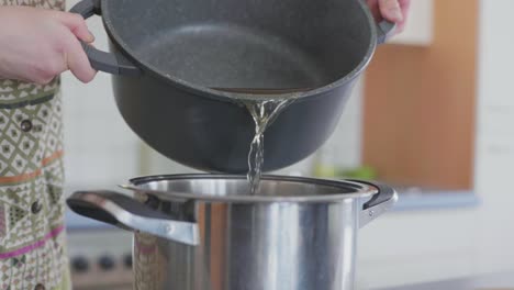 Slow-motion-of-soup-fond-boullion-being-poured-from-one-pot-into-another-by-a-female-chef