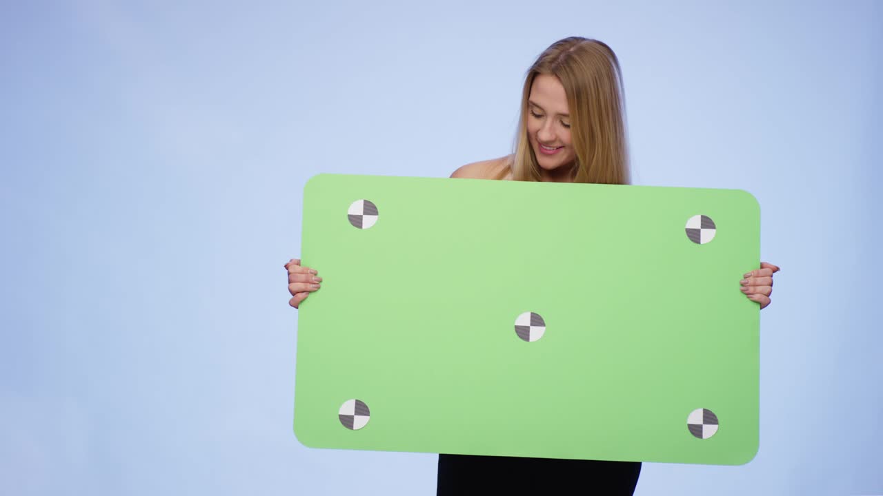 Cheerful Woman holding oversized blank Card and looking at it