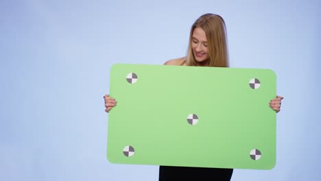 mujer alegre sosteniendo una tarjeta en blanco de gran tamaño y mirándola