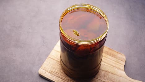 homemade mango pickle in a glass jar on table