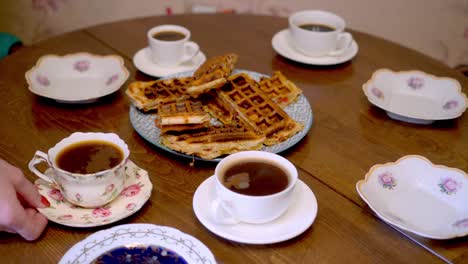 woman arranges cups and saucers on the table. dinner with tea and coffee.