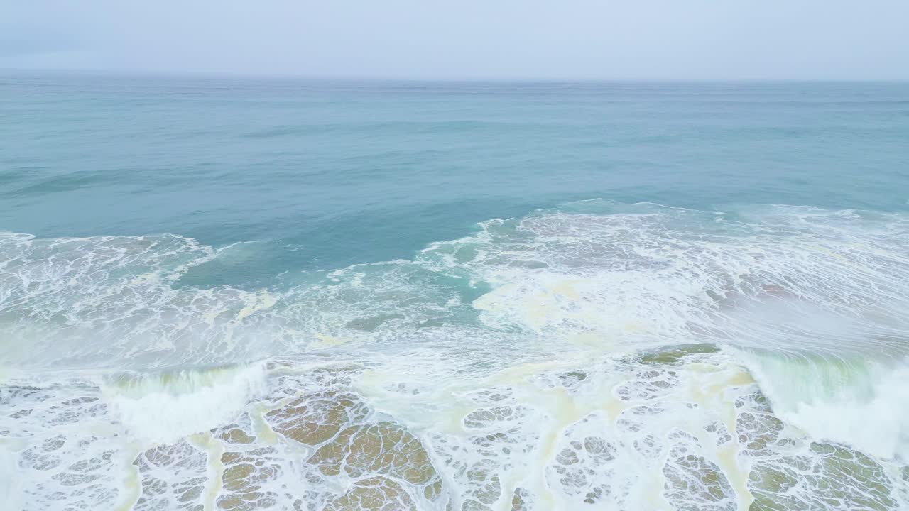 The ocean waves crashing on the shore of aljezur, portugal, aerial view