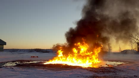 huge fire burns up an oil spill leaving huge thick black clouds of smoke drifting across the sky