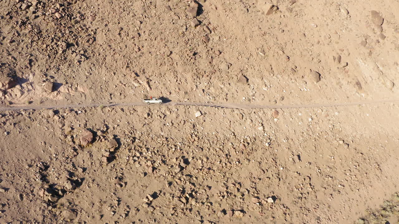camioneta blanca conduciendo por un peligroso camino de ripio junto al acantilado