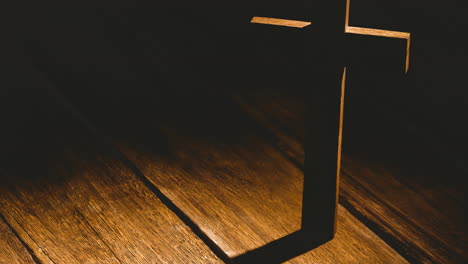 wooden christian cross casting shadow over wooden surface