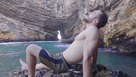 young man sunbathing in the sea cave.