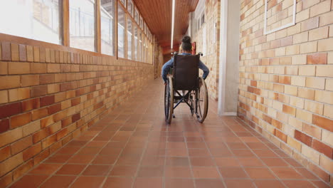 student in wheelchair moving through school hallway with brick walls