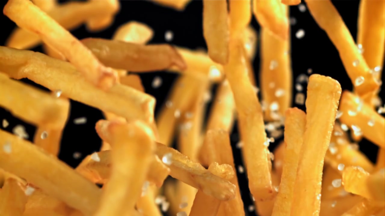 Goldene Pommes Frites fallen und werden gesalzen