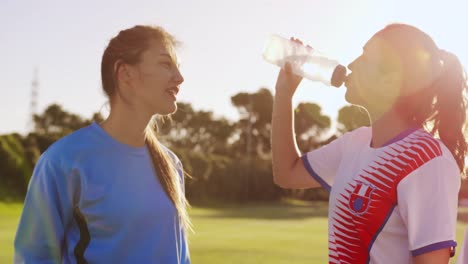 Side-view-of-female-soccer-players-drinking-water-4k