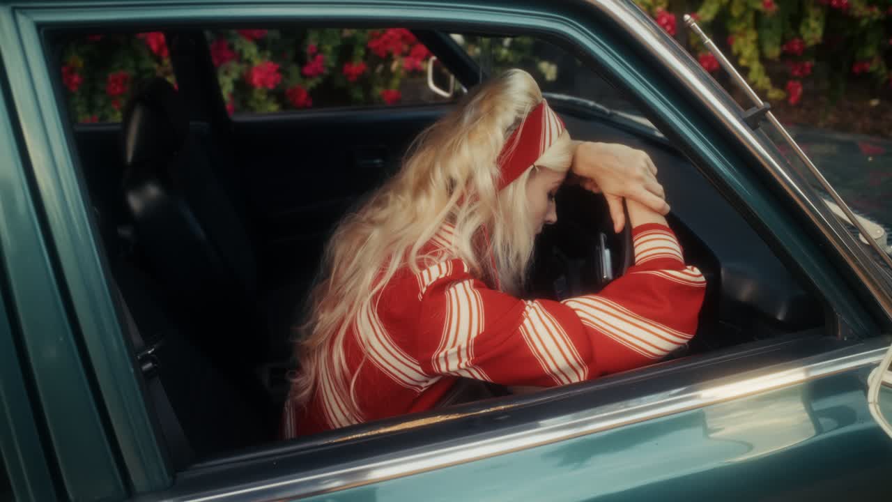 Nachdenkliche Frau im roten Shirt, die in einem Oldtimer wartet