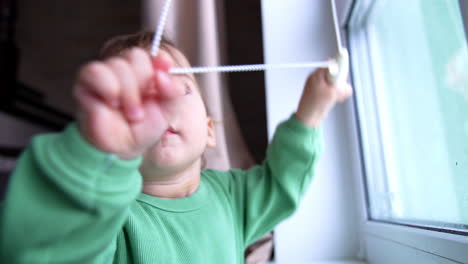 baby playing with window blinds