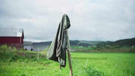 hooded jacket hanging on wooden fence pole at the field