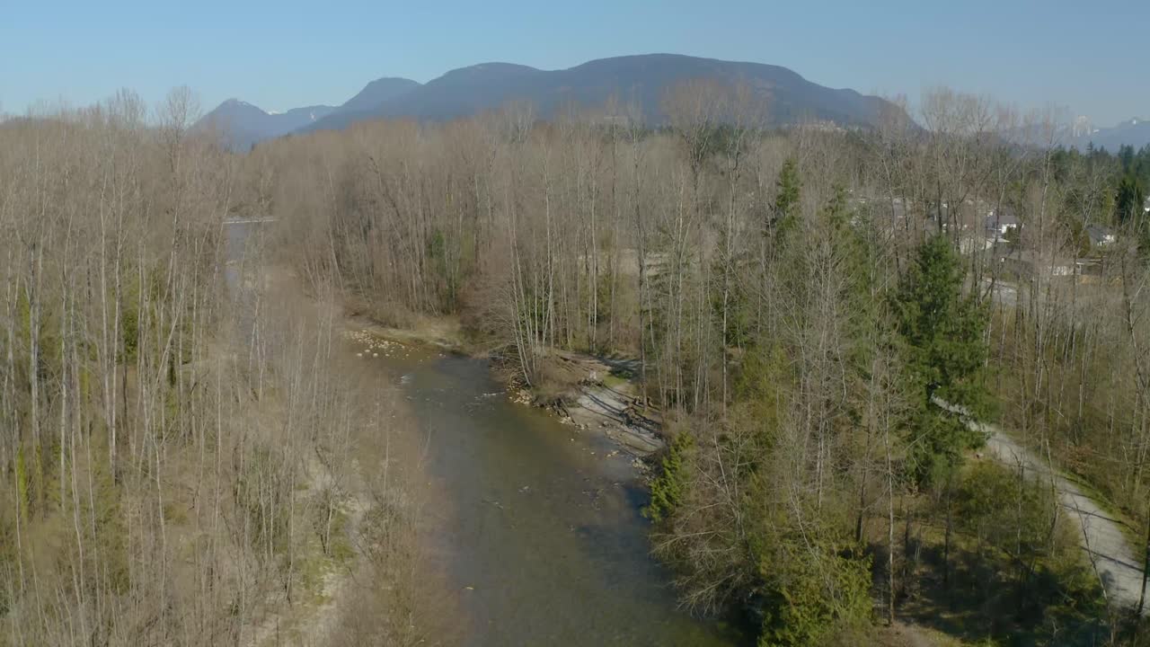 Suburban landscape with river and view of the mountains in the background. Above river bed.