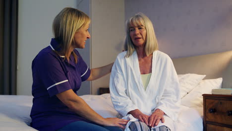 nurse talking with senior woman in bedroom on home visit