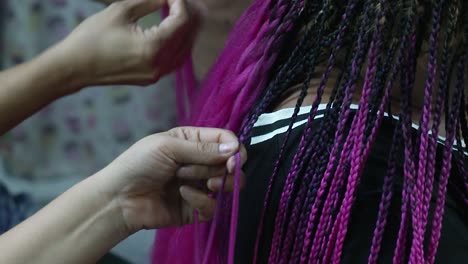 fast and skillful hair braiding of colorful hair, hair plaiting lacing interlacing, purple black gothic braid hair style