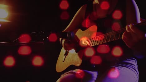 Animation-of-blurred-road-traffic-over-midsection-of-caucasian-woman-singing-and-playing-guitar