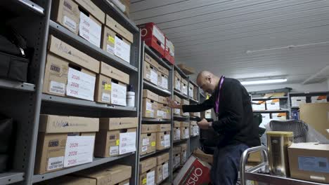 a man sifts through carton boxes within the business's stocked shelves, reflecting the concept of inventory management and organization in a commercial setting