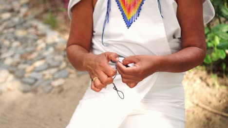 las manos de una mujer indígena de la sierra nevada de colombia haciendo tejidos tradicionales.