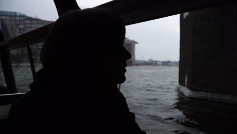 girl sail on a boat through the canals in amsterdam and looks out the window