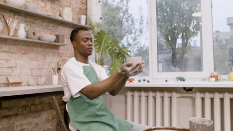 american clerk looking at a ceramic piece that he has modeled on the potter wheel 1