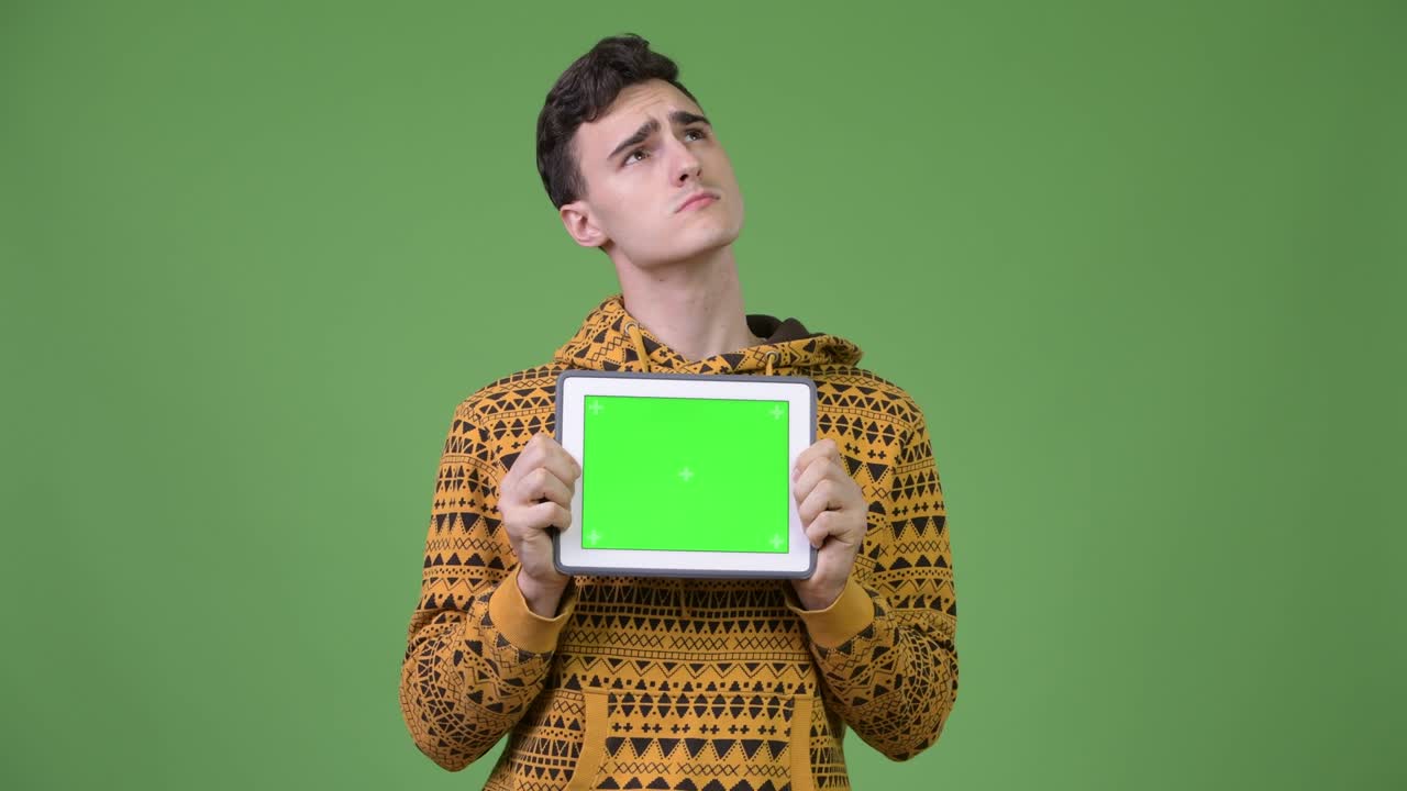 Young handsome man thinking while showing digital tablet